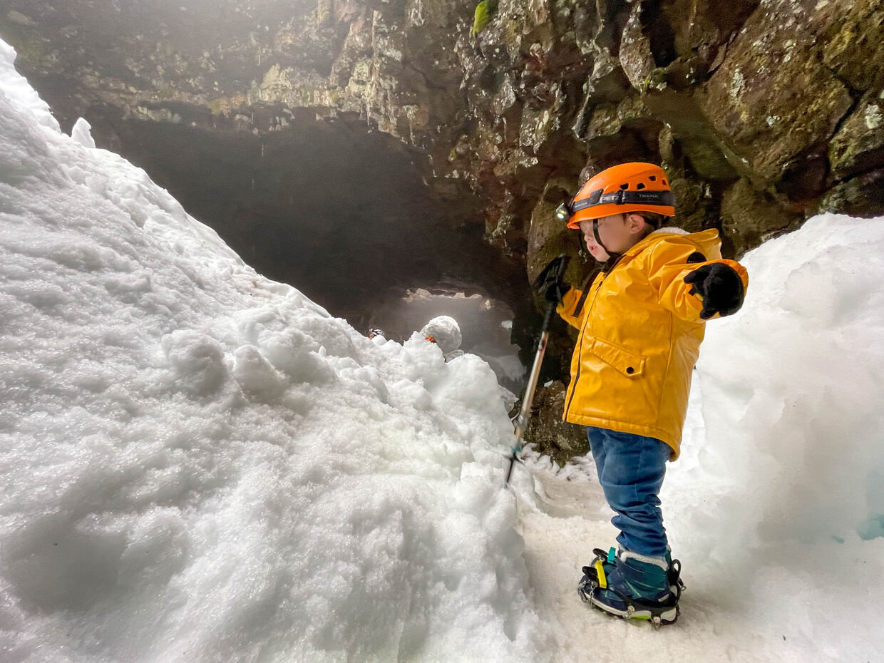 Conway with his crampons, helmet, and walking stick, in the snowy cave at Raufarhólshellir