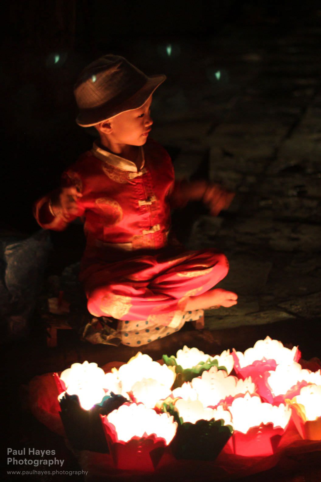 A child selling lanterns, sitting with the faeries